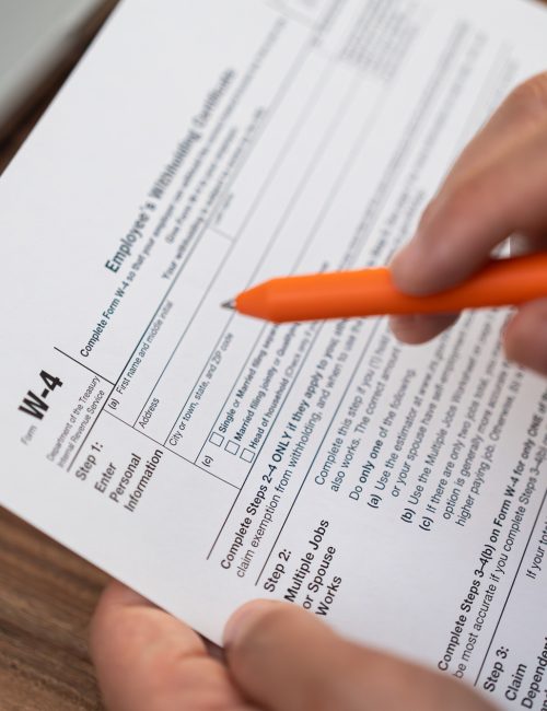 Male corporate intern sits with laptop at table in company office filling out W-4 form